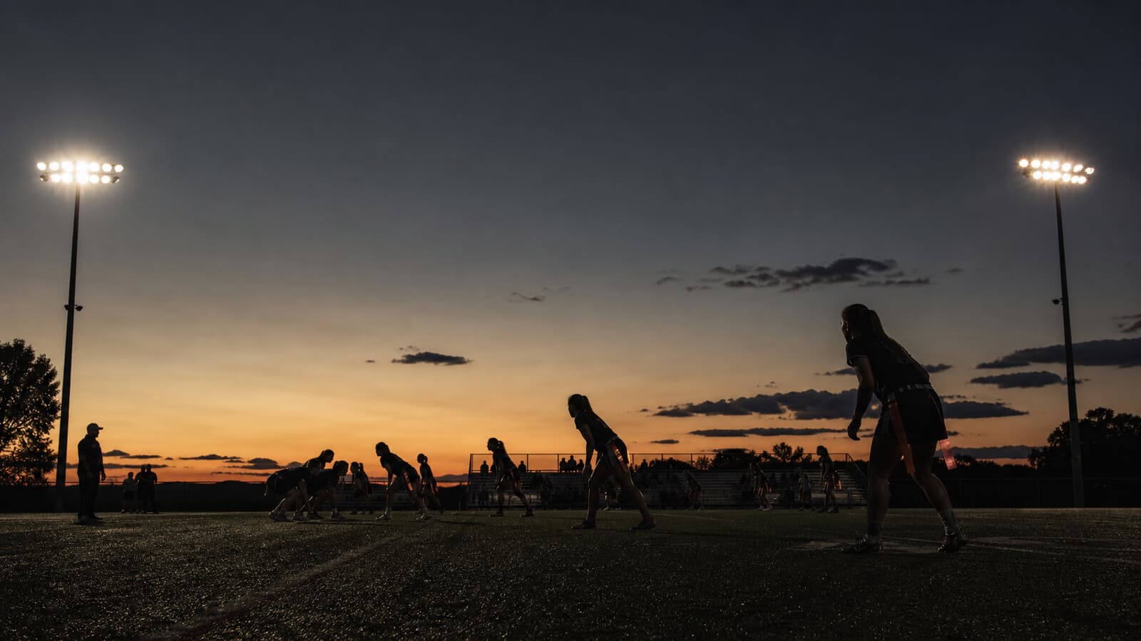 Twilight stadium lights illuminate silhouetted players mid-action.
